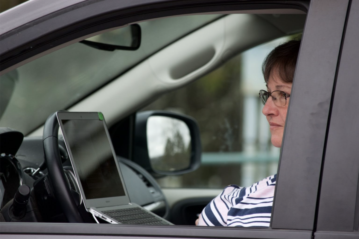 A school teacher accessing the Internet from her car in the school parking lot due to insufficient broadband access at home during the Covid pandemic.